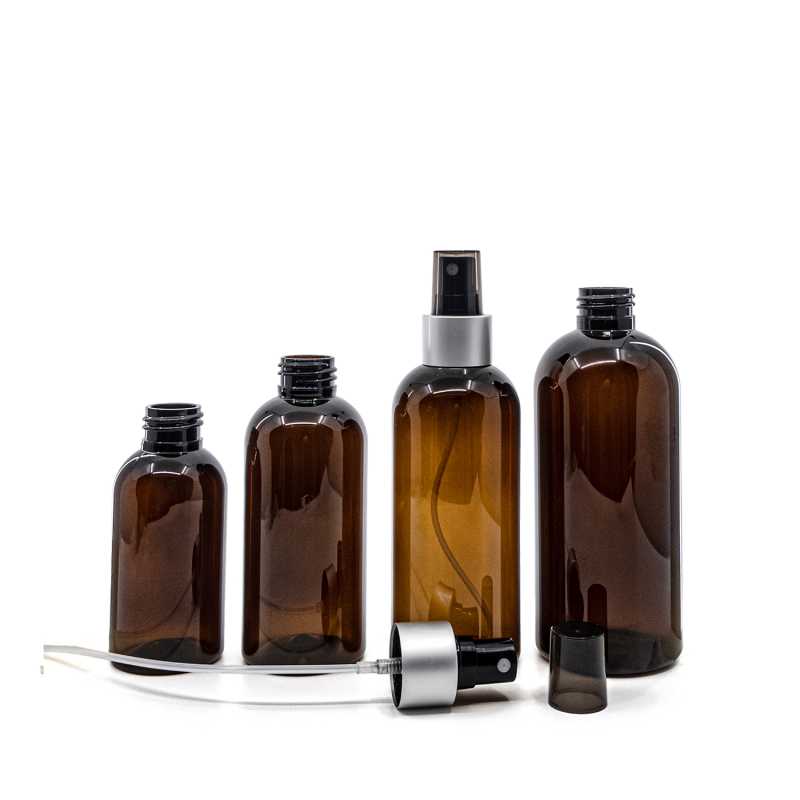 Bernsteinfarbene Kunststoffflasche, schwarzer Sprühkopf, matt-silberner Kragen, rauchfarbener Überka