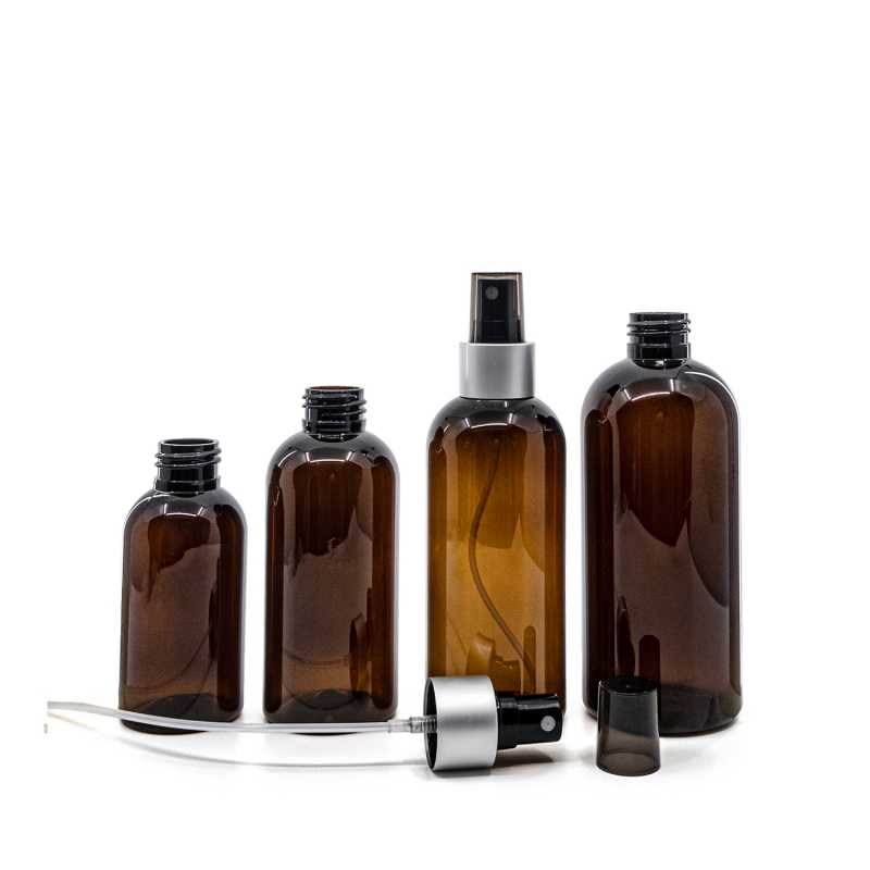 Bernsteinfarbene Kunststoffflasche, schwarzer Sprühkopf, matt-silberner Kragen, rauchfarbener Überka